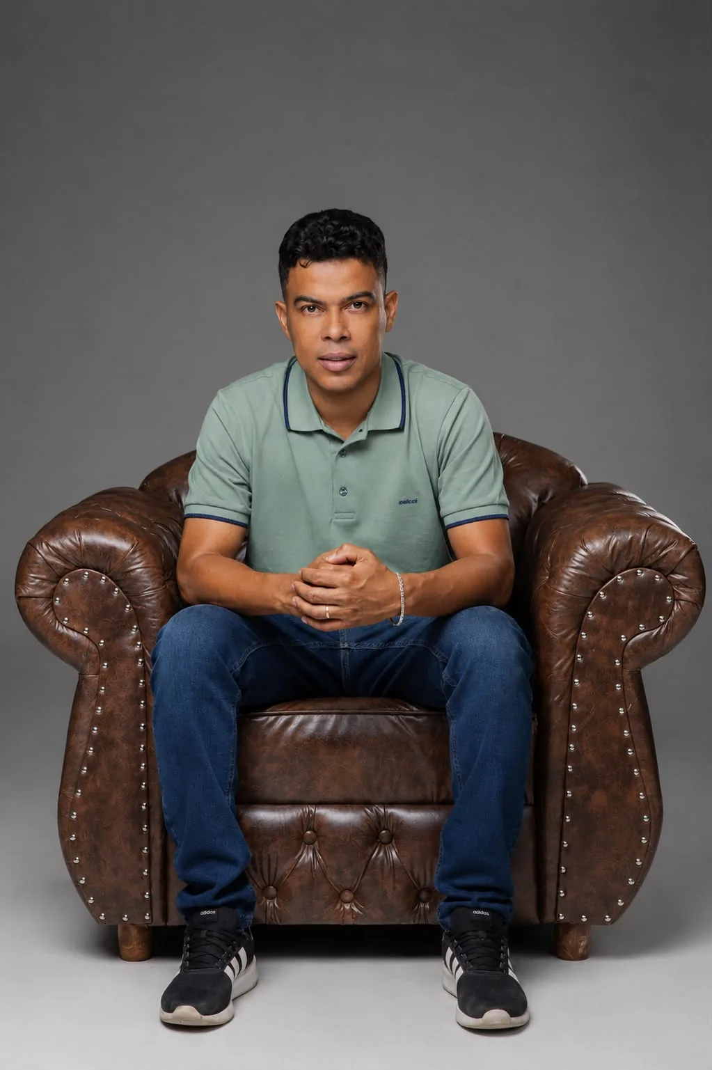 Nilson Santos sentado em poltrona de couro, de camisa polo verde, olhando para a câmera
